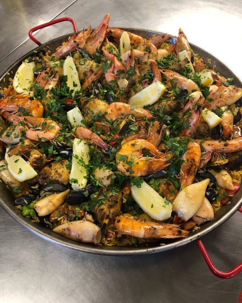 Paella Géante Fruits de Mer et Poulet Fraîcheur Grande paella de fruits de mer et poulet garnie de grosses crevettes, calmars, moules, citron et persil haché.