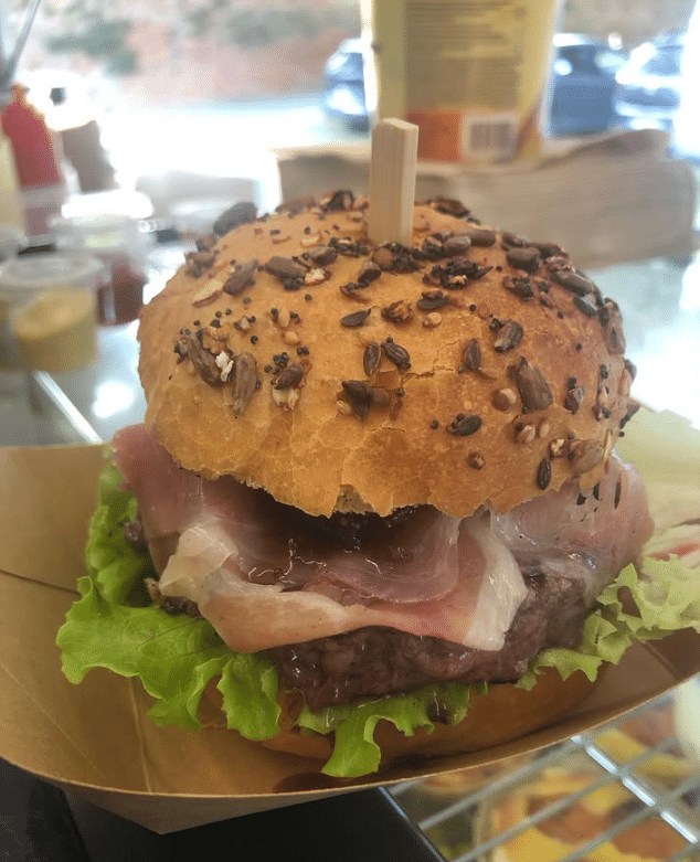 Burger Gourmet au Jambon Cru et Pain aux Graines Burger gourmet au pain multicéréales avec jambon cru, steak de bœuf juteux, salade et sauce onctueuse.